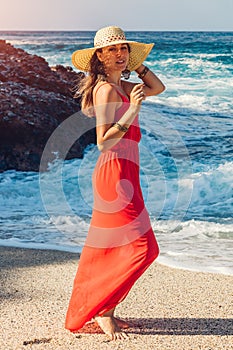 Beautiful woman enjoys the view of waves on sunny beach. Happy woman chilling out. Summer vacation concept