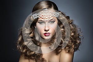 Beautiful woman with evening make-up and curls and big jewelry on her head. Beauty face.
