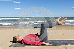 beautiful woman exercising on the beach with pilates ring