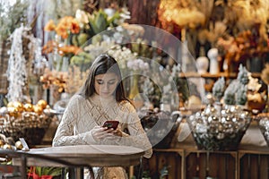 A beautiful woman explores the decor store with her phone in hand.