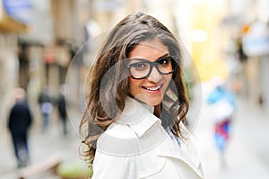 Beautiful woman with eye glasses smiling in urban background