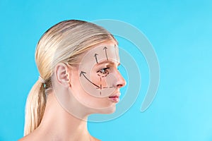 Beautiful Woman Face. Beauty Portrait of young woman blond, painted lines on the face for cosmetic surgery on blue