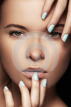 Beautiful woman face with blue nails manicure, clean skin