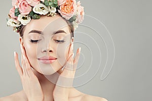 Beautiful woman face closeup. Healthy spa model with clear skin, manicured nails and flowers
