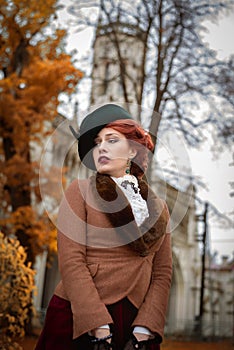 Beautiful woman face in the hat and red hair autumn trees