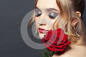 Beautiful woman face with makeup and red rose flower