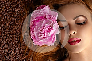 Beautiful woman face with peony on coffee beans