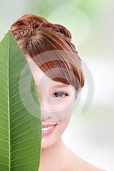 Beautiful woman face portrait with green leaf