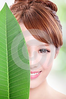Beautiful woman face portrait with green leaf
