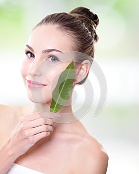 Beautiful woman face portrait with green leaf