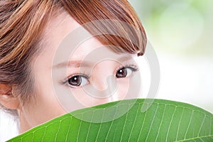 Beautiful woman face portrait with green leaf