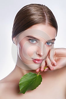 Beautiful woman face portrait with green leaf , concept for skin care or organic cosmetics