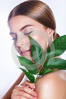 Beautiful woman face portrait with green leaf concept for skin care or organic cosmetics. Studio portrait