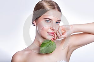 Beautiful woman face portrait with green leaf concept for skin care or organic cosmetics. Studio portrait