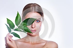 Beautiful woman face portrait with green leaf concept for skin care or organic cosmetics. Studio portrait