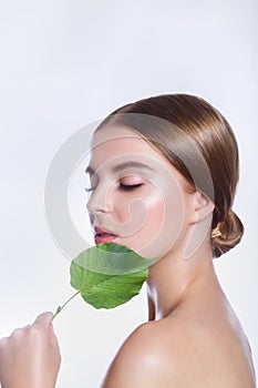 Beautiful woman face portrait with green leaf concept for skin care or organic cosmetics. Studio portrait