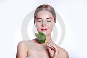 Beautiful woman face portrait with green leaf concept for skin care or organic cosmetics. Studio portrait