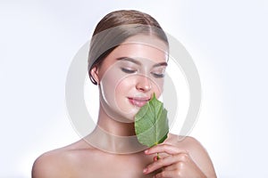 Beautiful woman face portrait with green leaf concept for skin care or organic cosmetics. Studio portrait