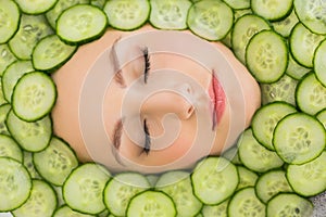 Beautiful woman with facial mask of cucumber slices on face