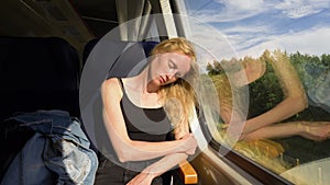 Beautiful woman falls asleep in the train. Female sleeps while having train trip home after work. Scandinavian look