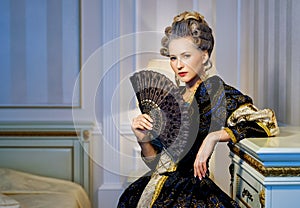 Beautiful woman with fan in historical dress in Baroque style in