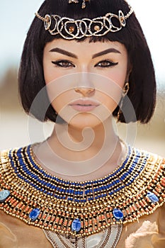 Beautiful woman with fashion make-up and hairstyle like Egyptian queen Cleopatra outdoors against desert