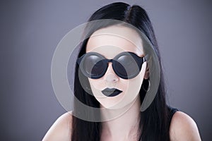 Beautiful woman fashion model portrait in sunglasses with black lips and earrings. Creative hairstyle and make up