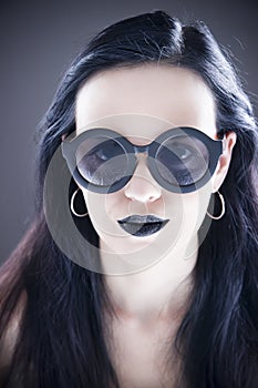 Beautiful woman fashion model portrait in sunglasses with black lips and earrings. Creative hairstyle and make up