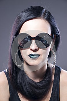 Beautiful woman fashion model portrait in sunglasses with blue lips and earrings. Creative hairstyle and make up