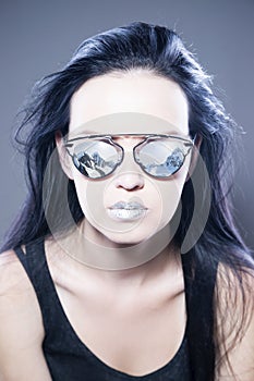 Beautiful woman fashion model portrait in sunglasses with reflections of mountains and metallic silver lips. Creative hairstyle an