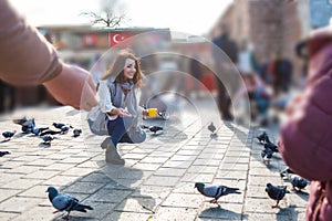 Beautiful woman in fashionable modern clothes feeds pigeons