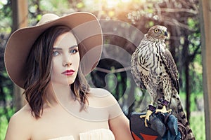 Beautiful woman in fedora hat with bird, outdoors portrait