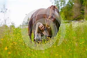 Beautiful woman feeding her arabian horse in the field