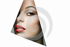 Beautiful woman. female face with makeup into paper hole