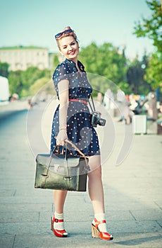 Beautiful woman in fifties style with braces holding retro camera