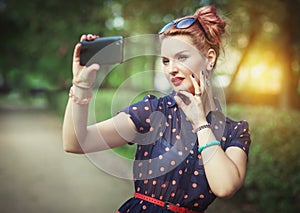 Beautiful woman in fifties style taking picture of herself