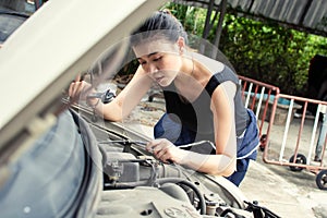 A beautiful woman is fixing broken machine in car