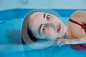 Beautiful woman floating in tank filled with dense salt water used in meditation, therapy, and alternative medicine