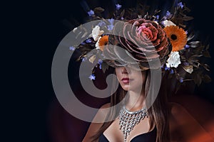 A beautiful woman with floral headdress poses amidst lush leaves and blooms in an artistic botanical portrait photo