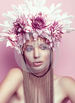 Beautiful woman with flower crown and makeup on pink background