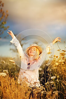 Beautiful woman in a flower meadow with sunhat and sunglasses, lust for life