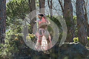 Woman dancing in a forest flicking her hair with trees in the background.