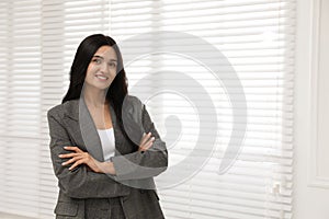 Beautiful woman in formal suit near window, space for text. Business attire