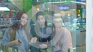 Beautiful woman friends looking at showcase in mall. 4K.