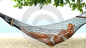 Beautiful woman full of vitality reclining suntanning in a hammock