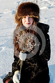 Beautiful woman in a fur coat and fur hat on a white snowy background