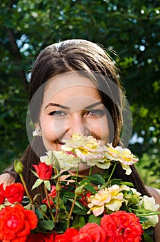 Beautiful woman in the garden smelling flowers.