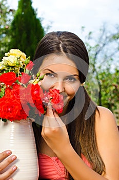 Beautiful woman in the garden smelling flowers.