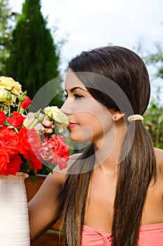 Beautiful woman in the garden smelling flowers.