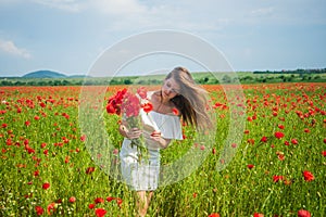 Beautiful woman gather red poppy flower bouquet in field. summer or spring nature. seasonal beauty landscape. young girl